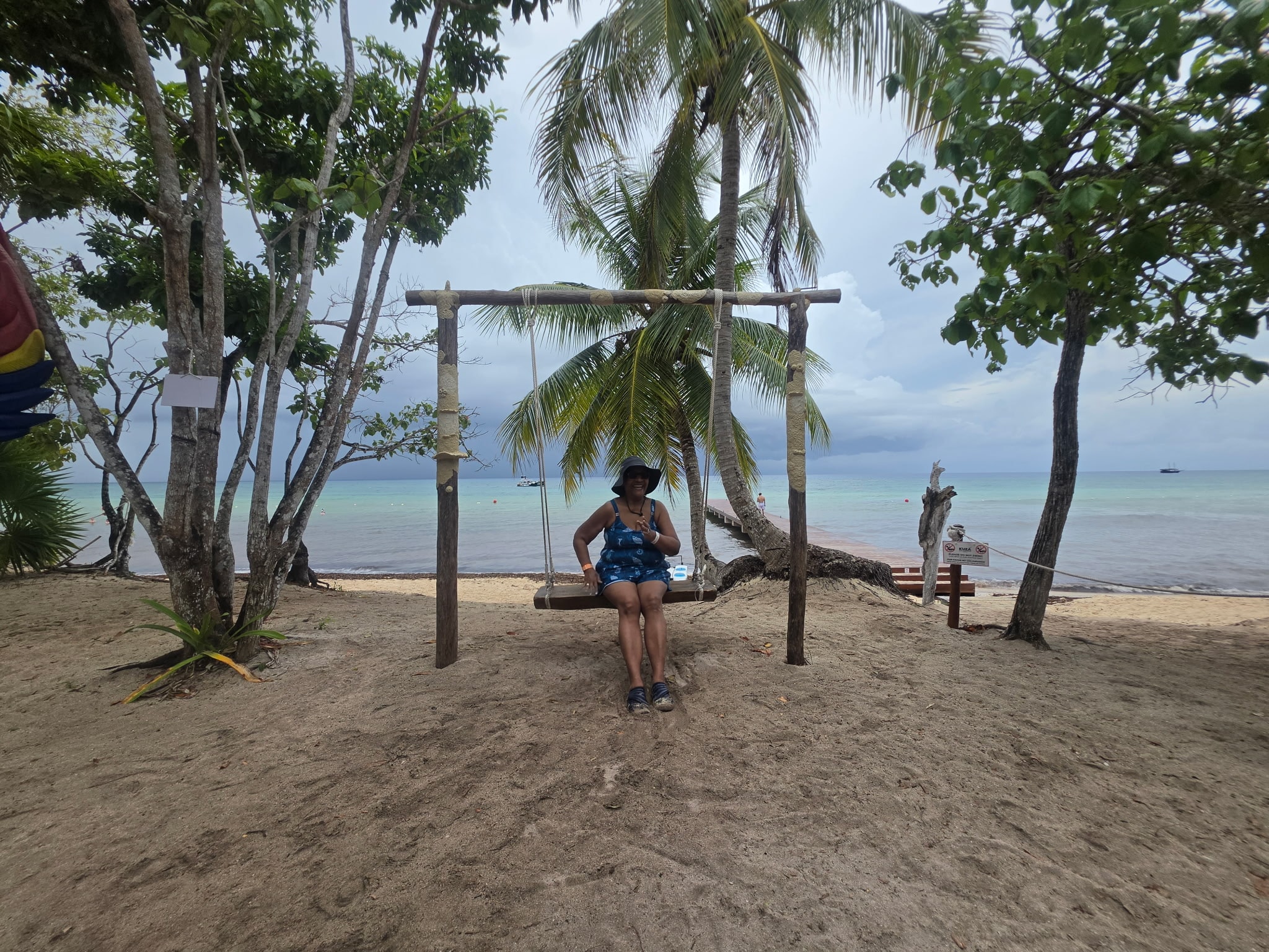 Jean relaxing on a beach swing with palm trees and turquoise water